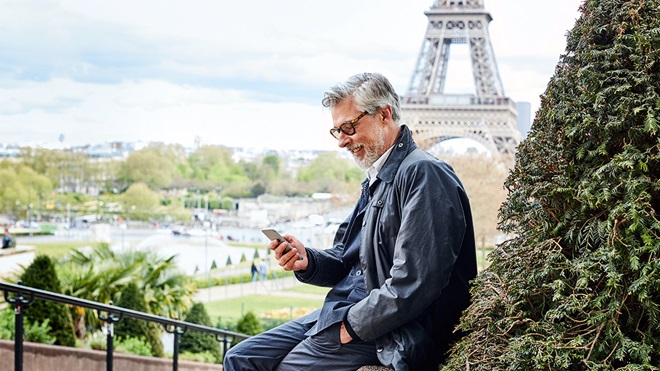 grey-haired man in Paris checking a language app on his phone
